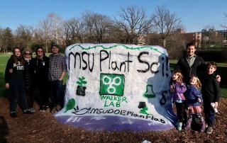 Rock painted by the Walker lab, three kids stand in the front.
